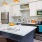 Kitchen with bar and seating, oven, microwave, refrigerator, dishwasher, and sink. Accent lighting is above the bar
