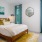 Bedroom with queen-sized bed, yellow accent rug, oversized windows and wall art